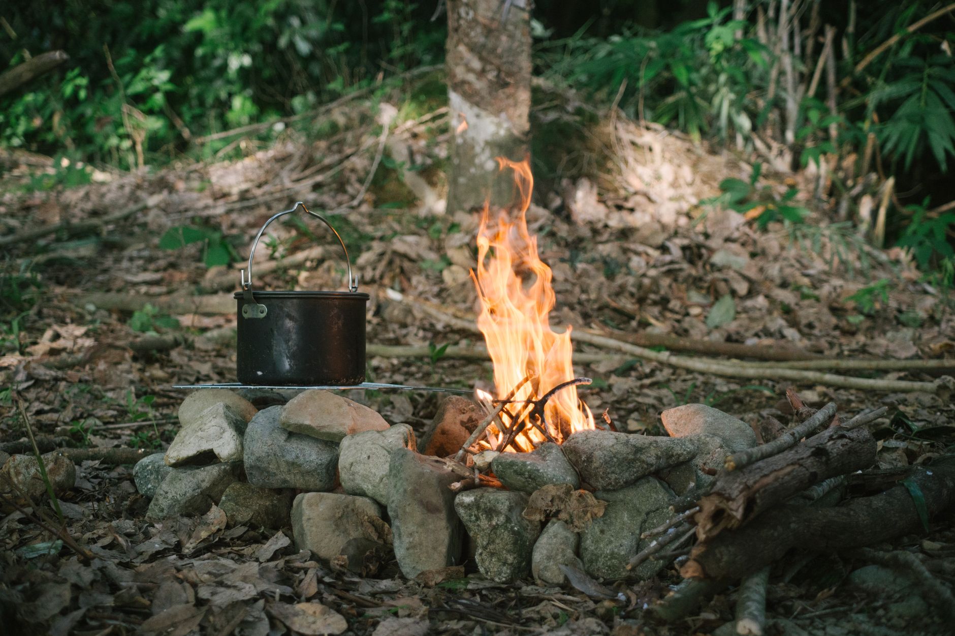 a pot standing next to a campfire