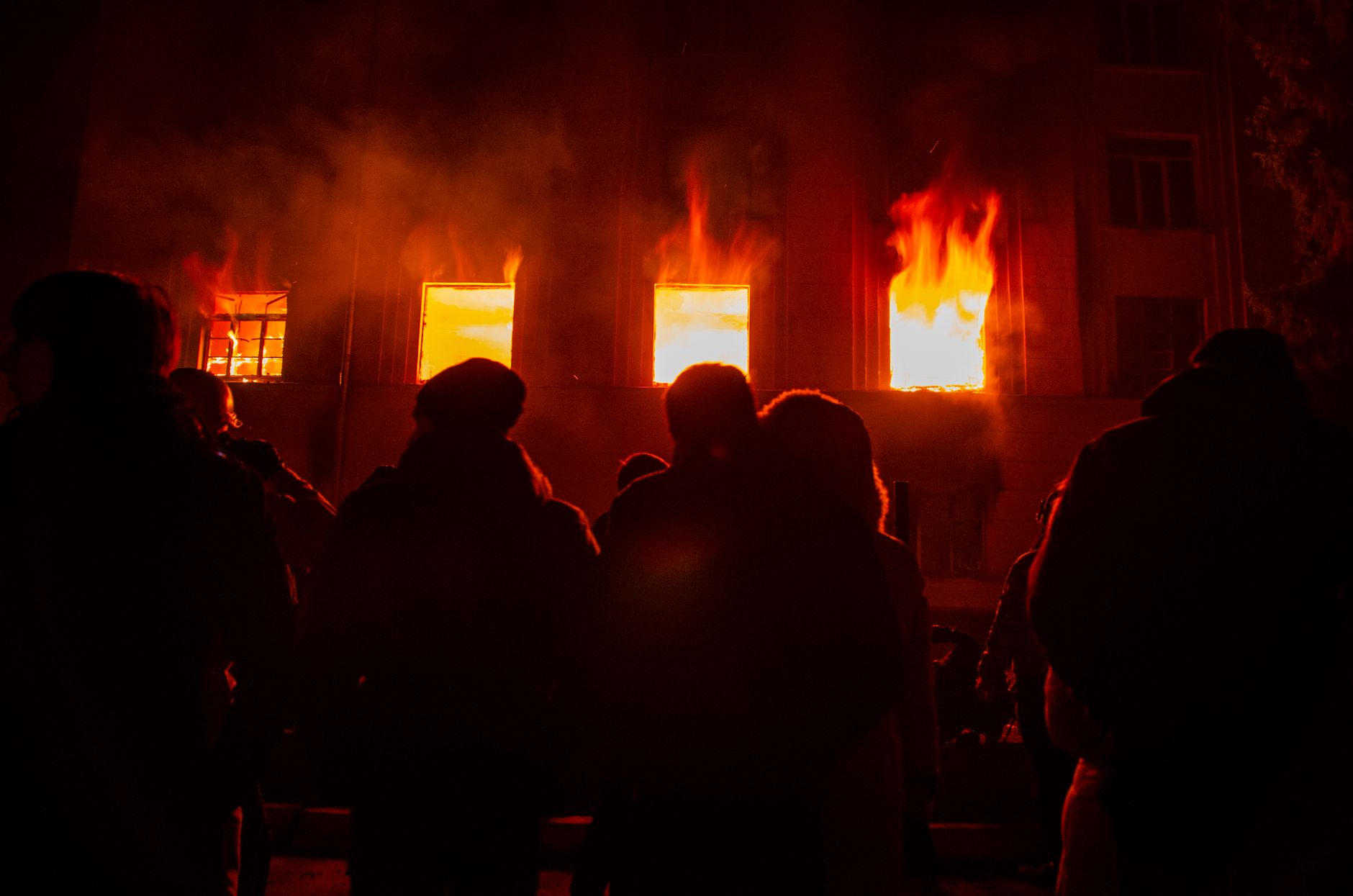 people standing in front of burning building