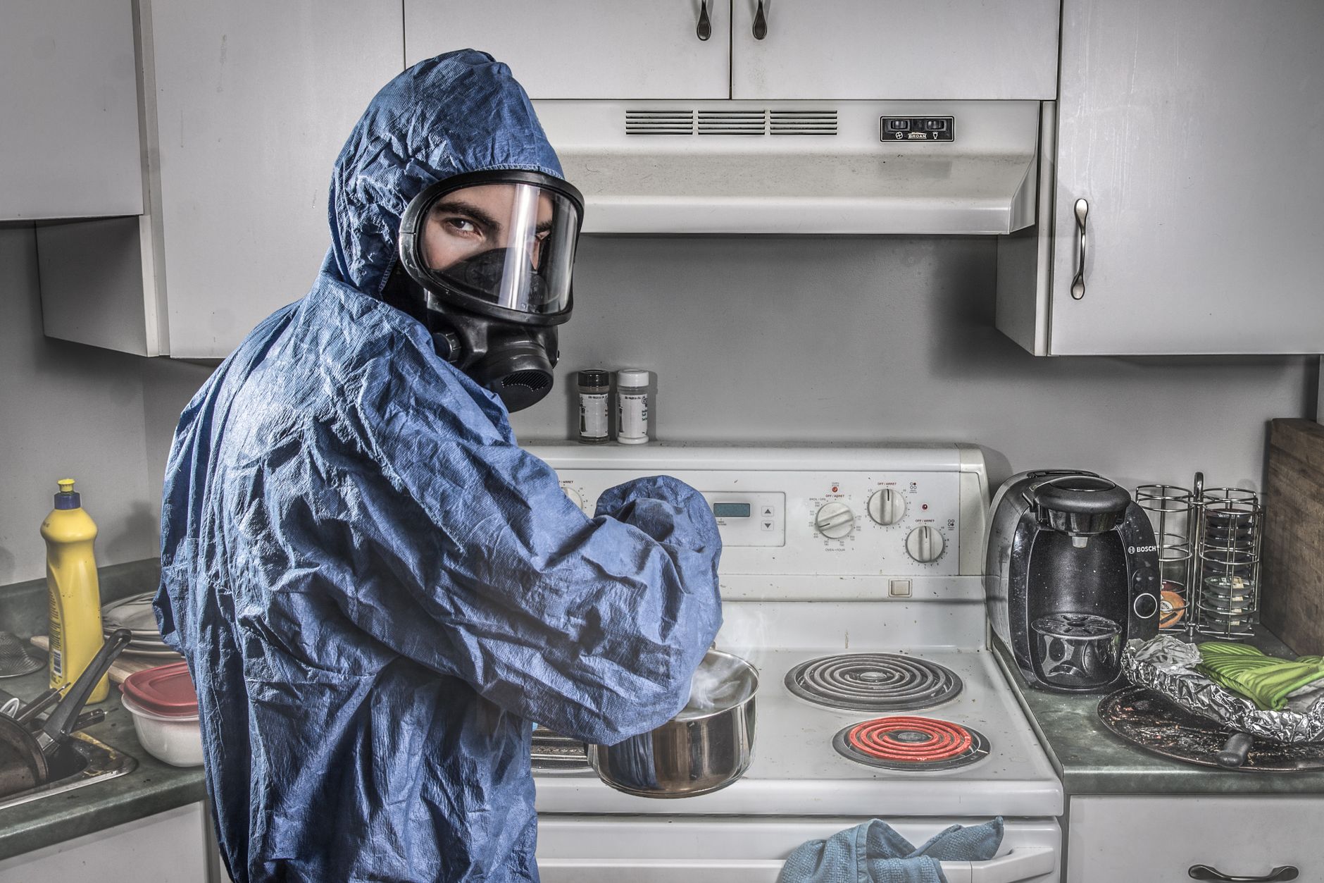 male chemist in protective respirator and suit in kitchen